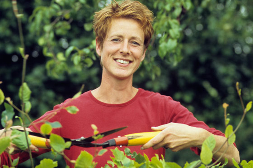 Een vrouw die een haag snoeit